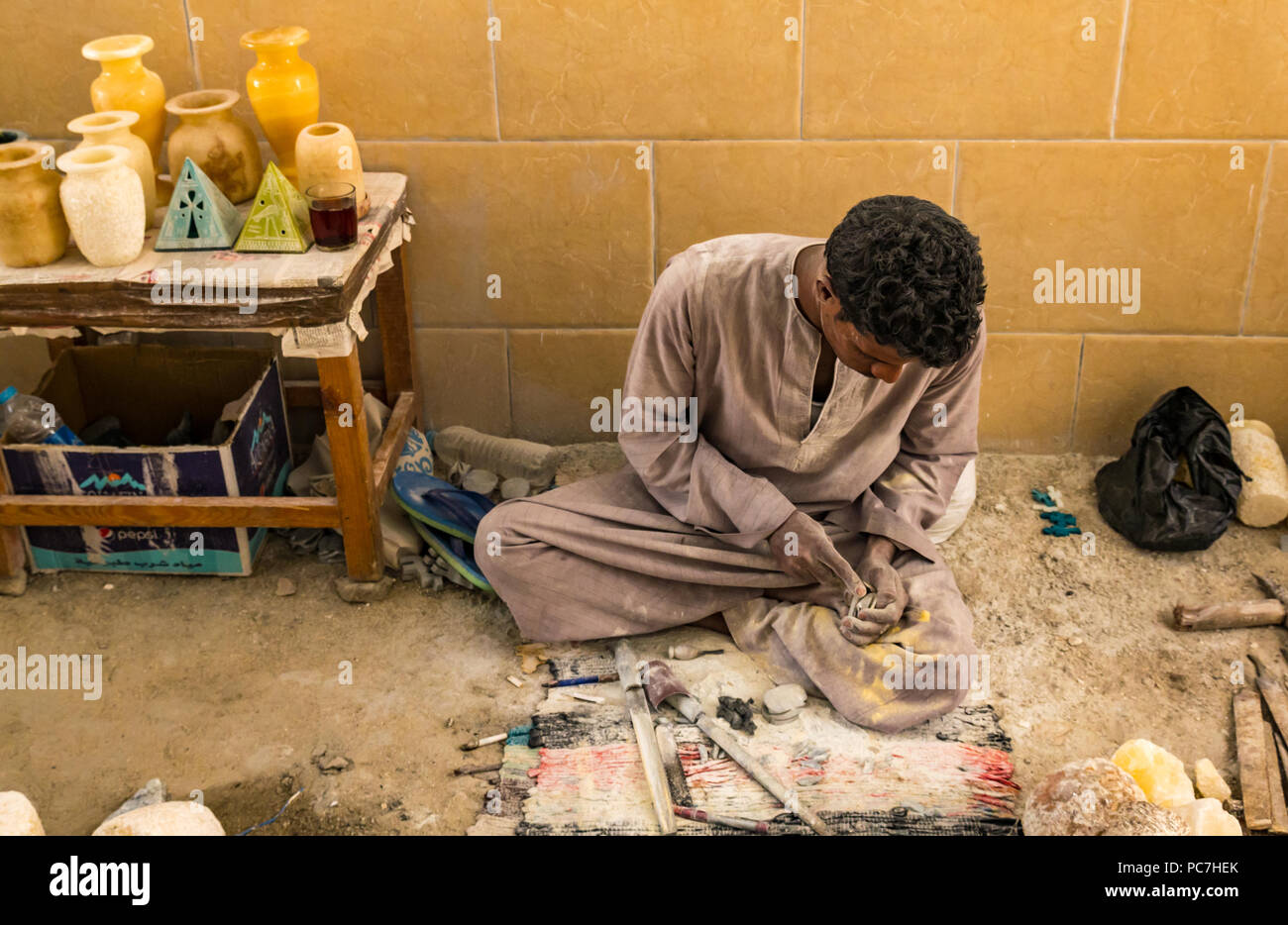 Egyptian workman using carving tool to carve alabaster container in