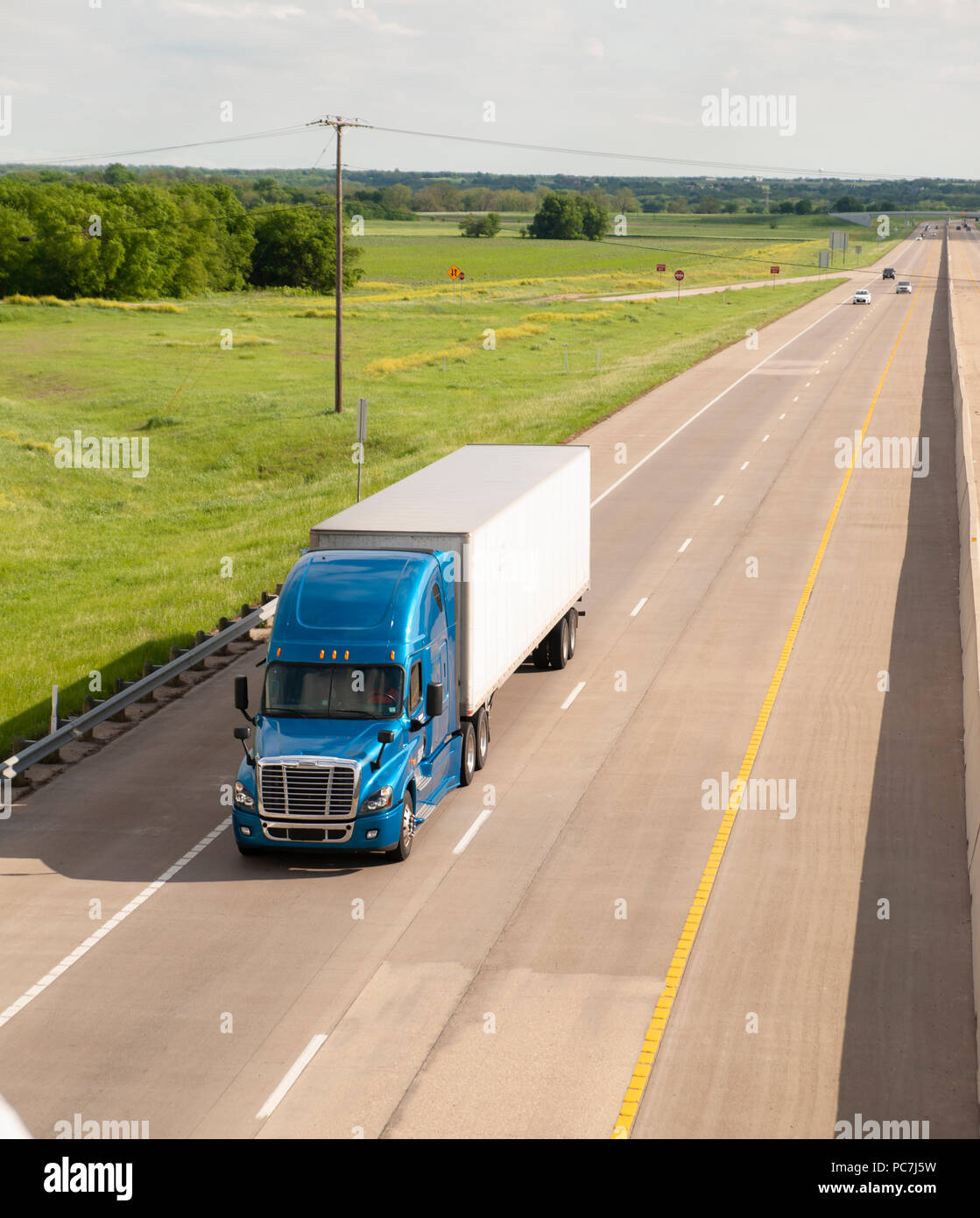 A bright and colorful 18 Wheeler motors down the highway with trailer attached Stock Photo