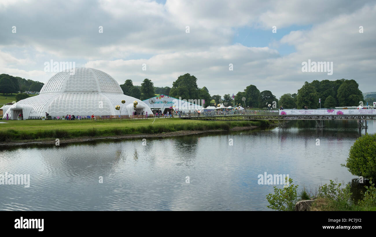 Showground at RHS Chatsworth Flower Show (people visiting, marquee, tents, Great Conservatory dome, river & temporary bridge) Derbyshire, England, UK. Stock Photo