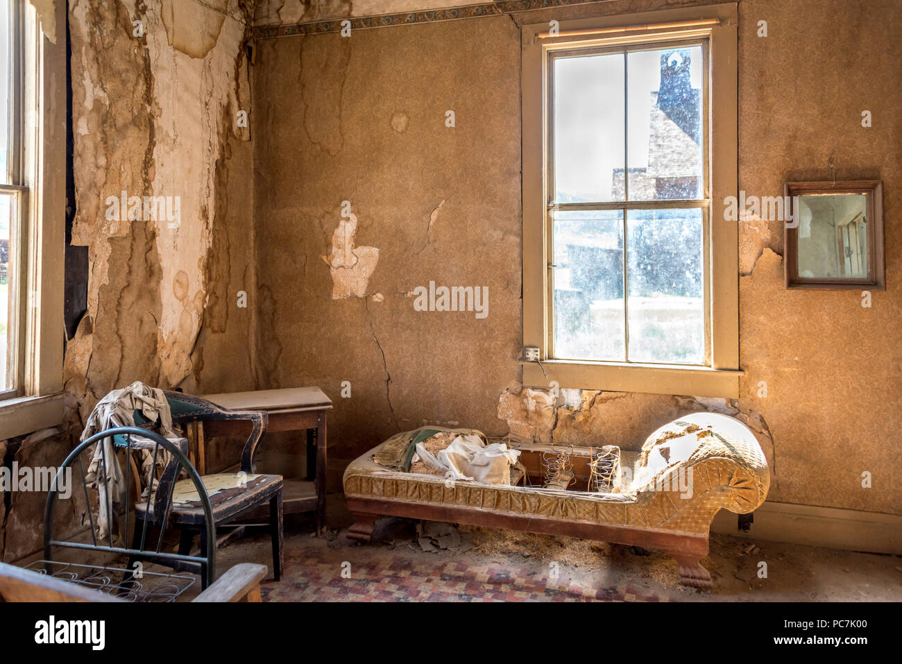 Interior of the Miller house w/ peeling wallpaper, cracked plaster, deteriorating furniture, at Bodie State Historic Park, a California ghost town. Stock Photo