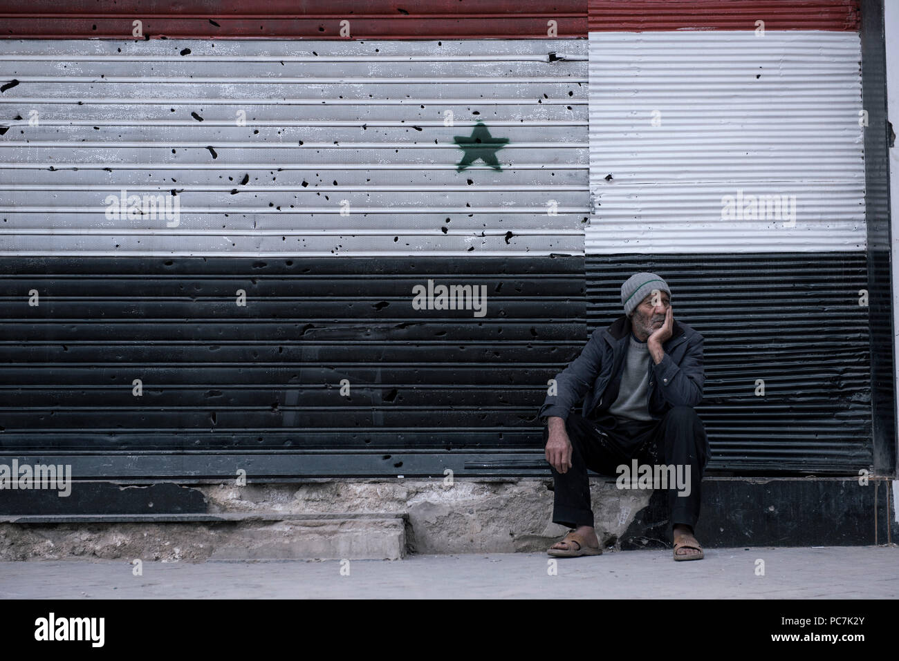 An old man from 'kafr btna-al ghota' set in front of his damaged store. Stock Photo