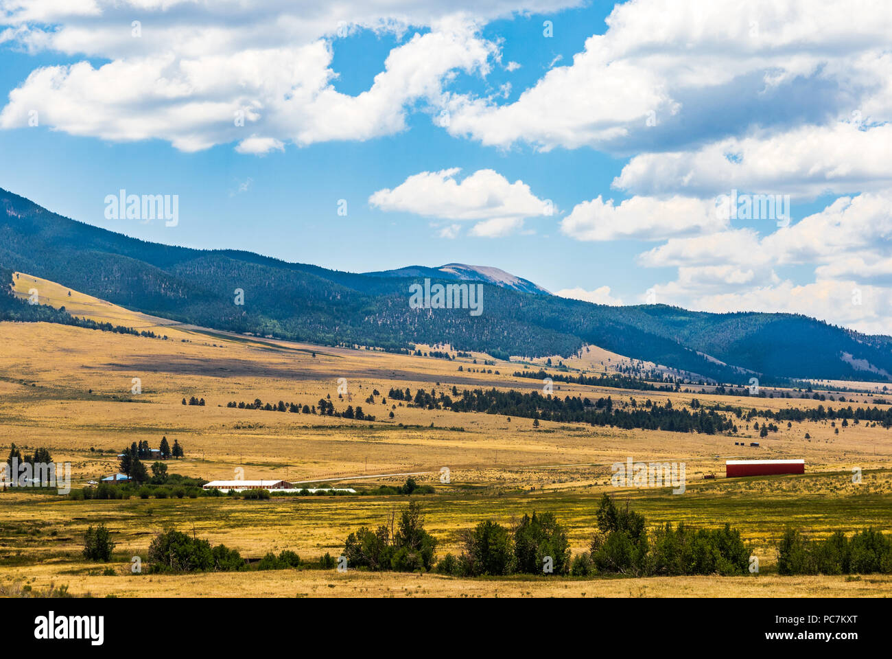TAOS, NM, USA-8 JULY  18: A mountain farmland scene in northwest New Mexico  near Taos includes  a red barn and other buildings in the midground. Stock Photo