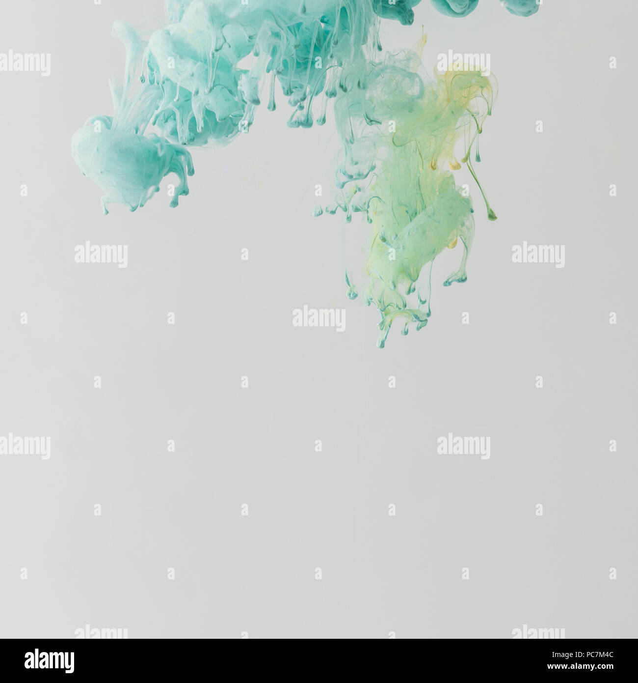 light turquoise paint flowing in water with drops, isolated on grey ...