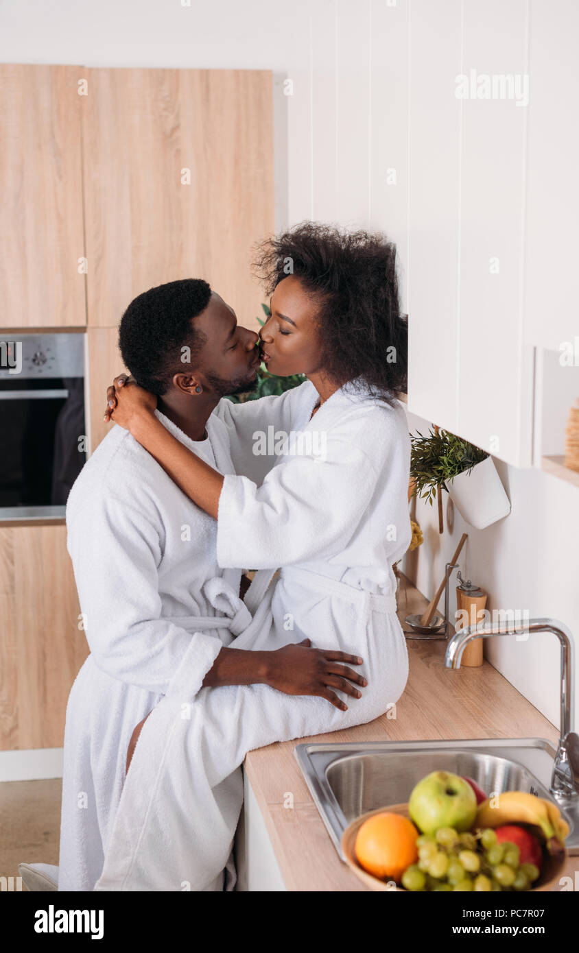 Side view of african american couple kissing in kitchen Stock Photo