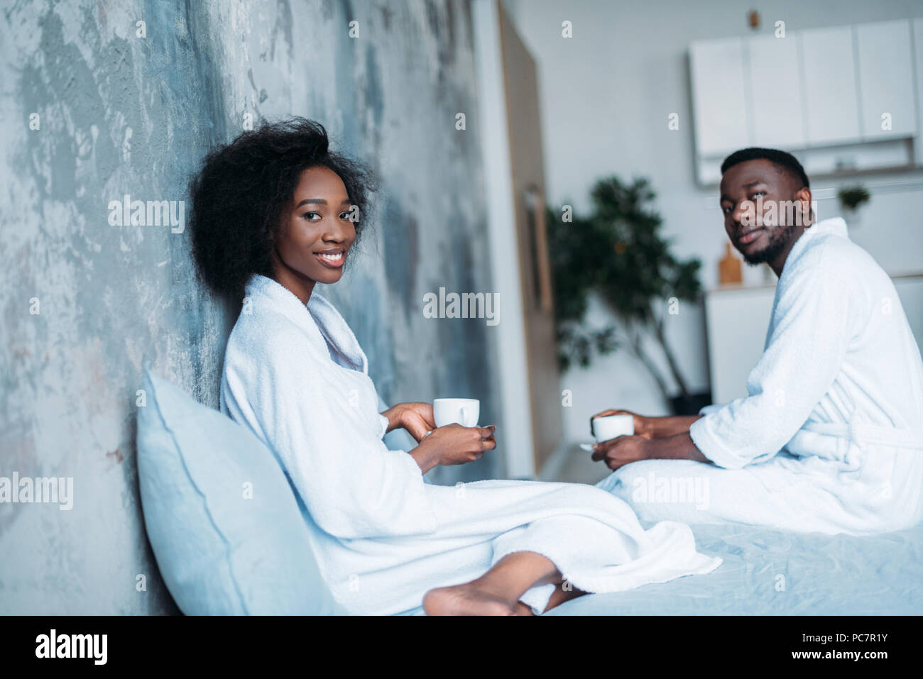 Smiling african american couple with coffee cups in bed Stock Photo