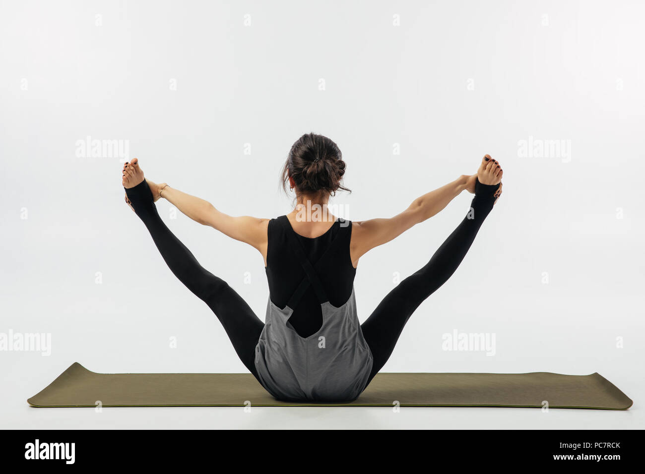 rear view of woman practicing yoga asana urdhva upavistha konasana isolated on white Stock Photo