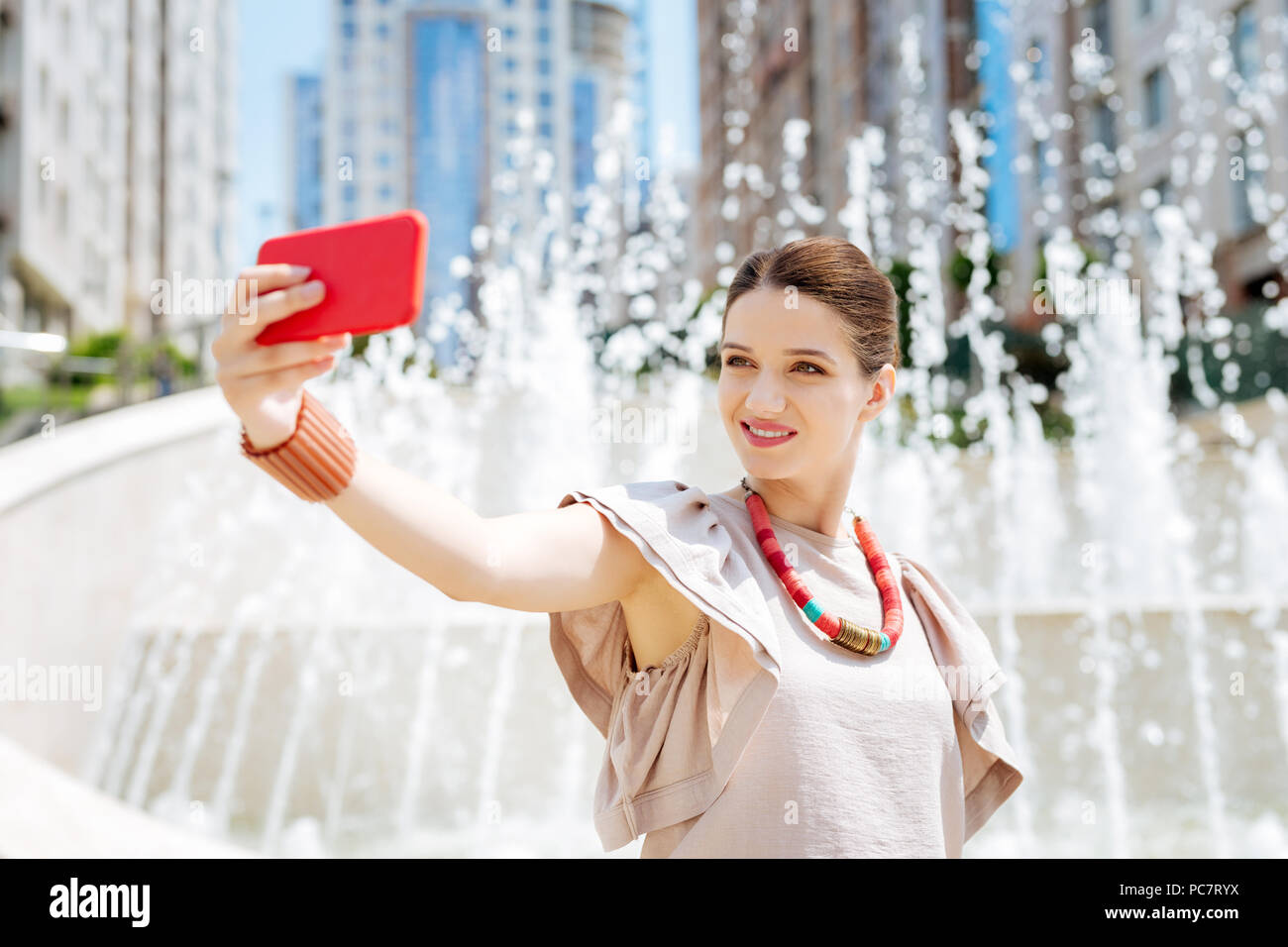 Delighted pretty woman using her smartphone camera Stock Photo