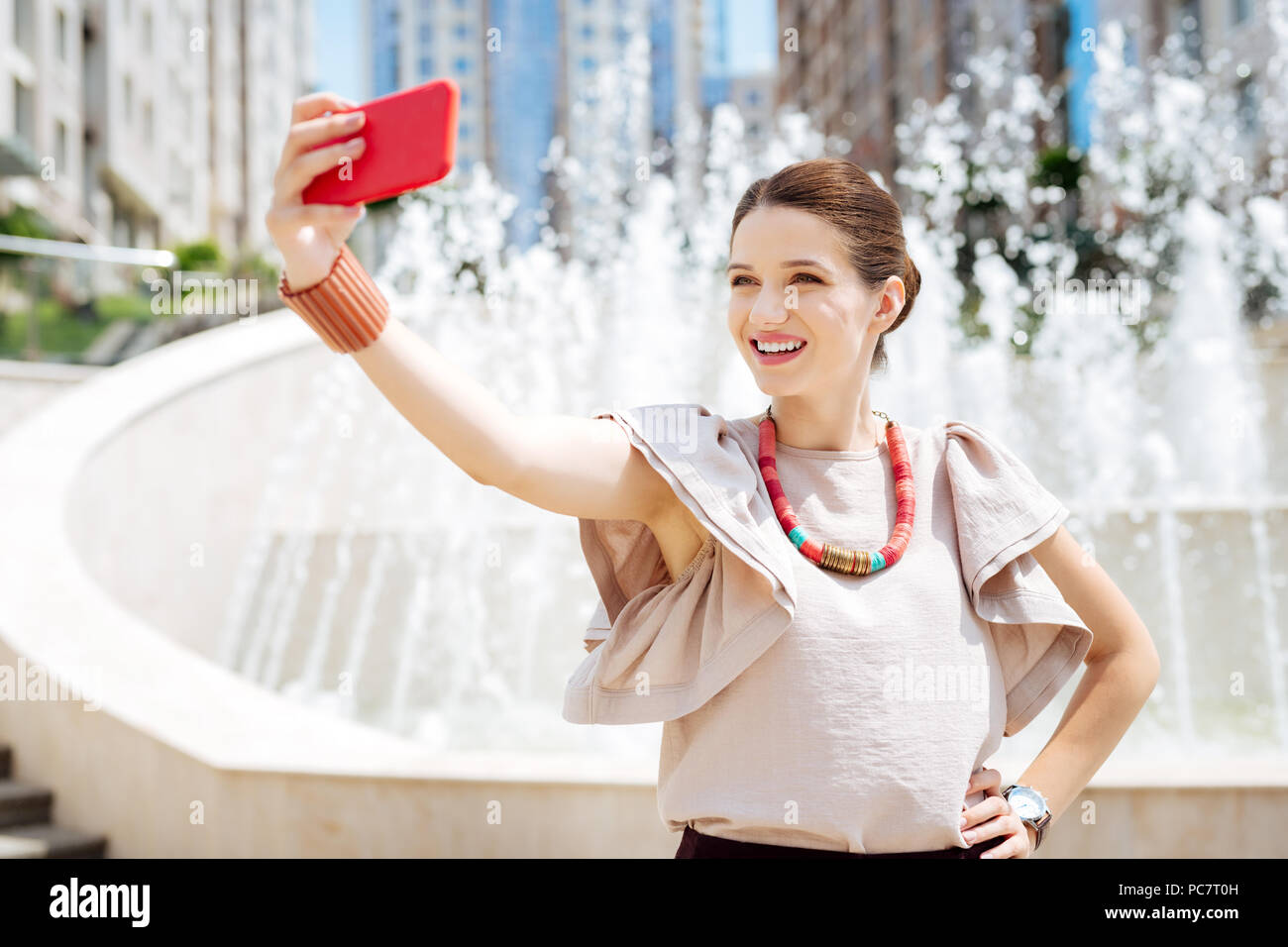 Attractive joyful woman looking into the smartphone camera Stock Photo