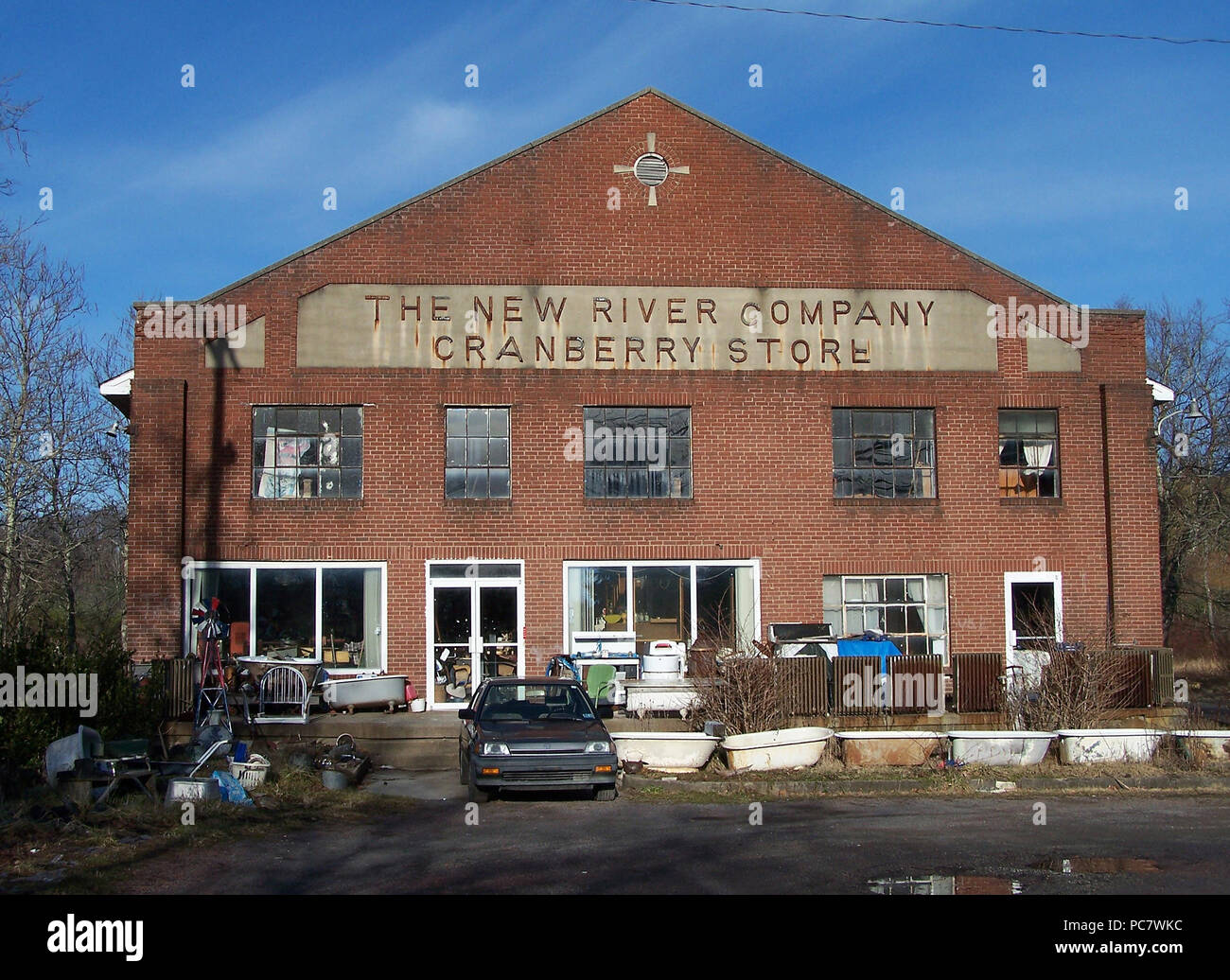 Constructed of brick with a stone lintel inscribed with 'New River Company Cranberry Store,' the building has fallen upon hard times, as witnessed by the numerous bathtubs and radiators positioned on the porch and in front of the building, as well as piles of unknown materials inside. Stock Photo