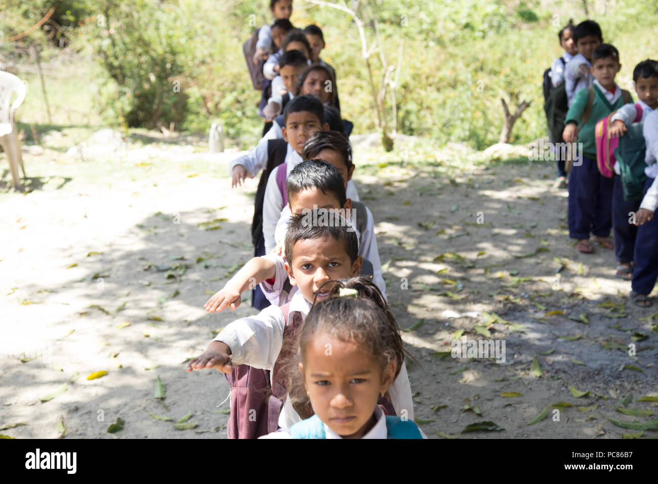 Village elementary school kids forming line for morning prayer. different age group children wearing school uniform. Stock Photo