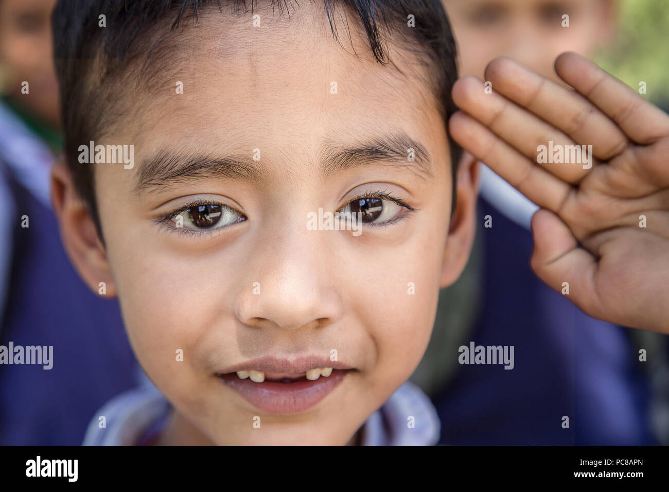 Portrait of adorable young Indian poor kid attending morning assembly in rural elementary school. Stock Photo