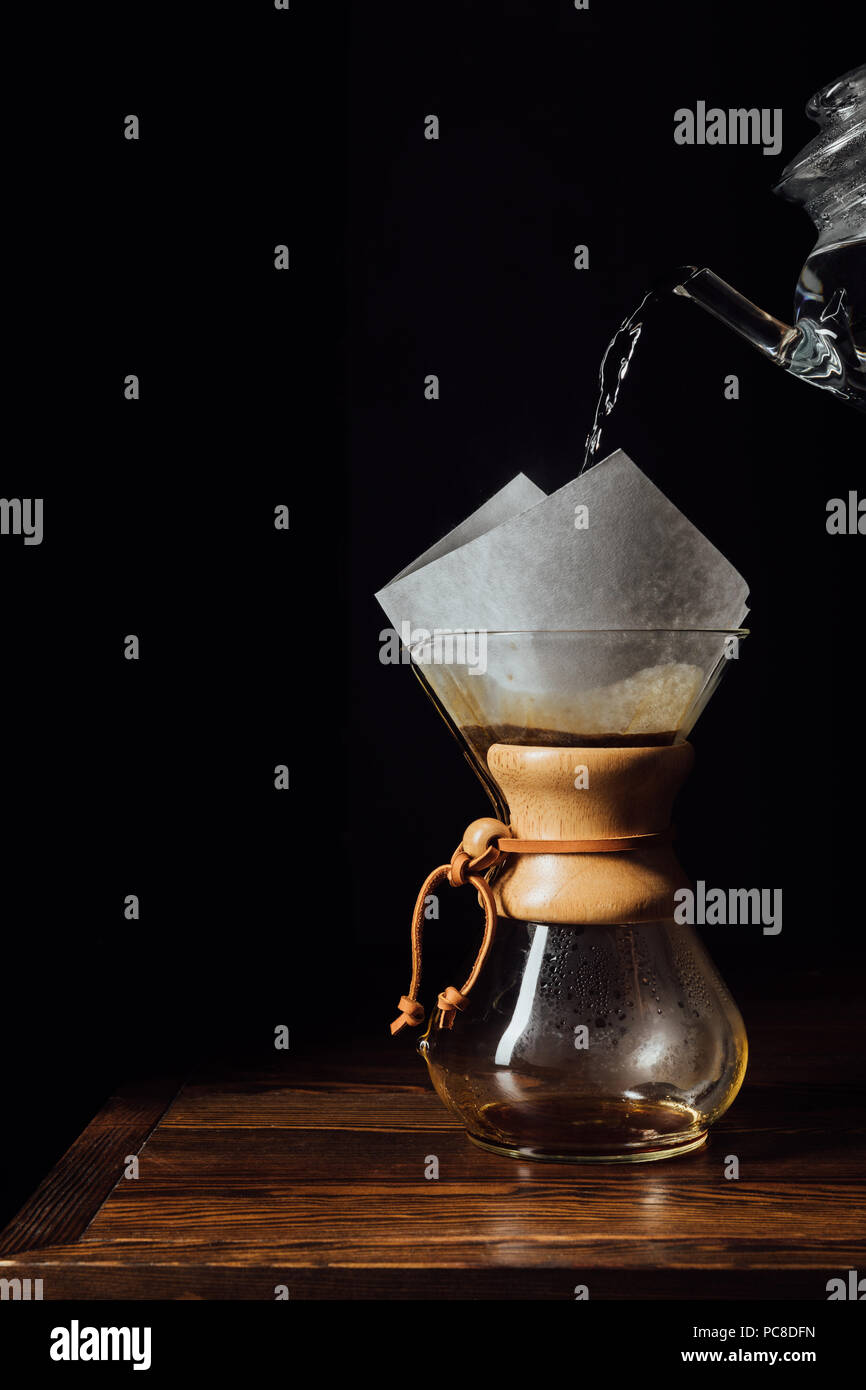Hot water pouring into chemex with filter cone on wooden table Stock Photo