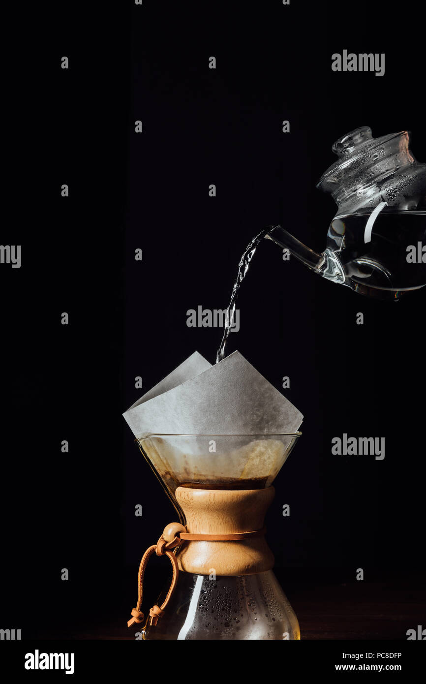 Hot water pouring into chemex with filter cone, isolated on black Stock Photo