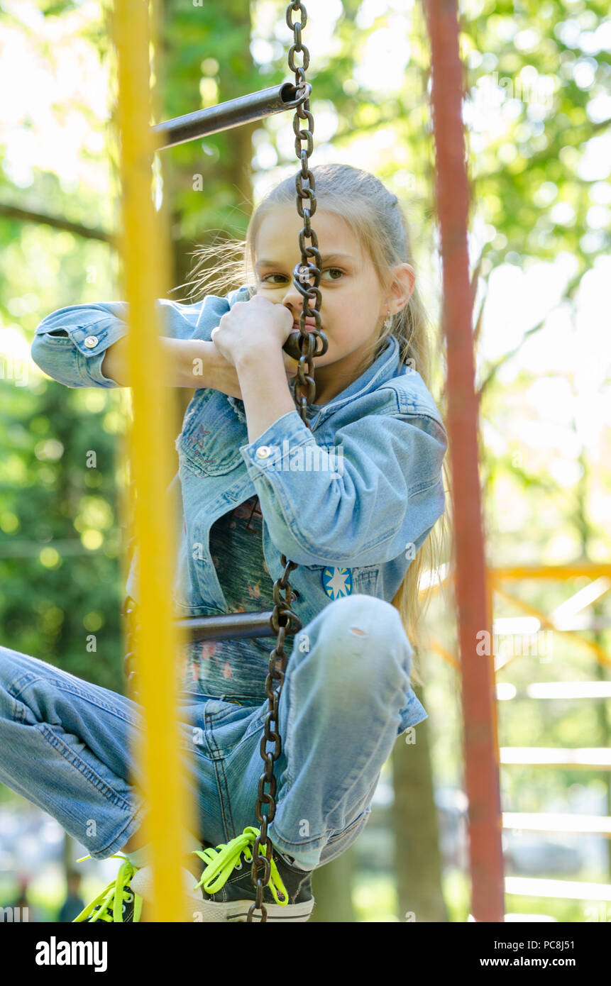 The girl pondered climbed the hanging ladder in the playground Stock
