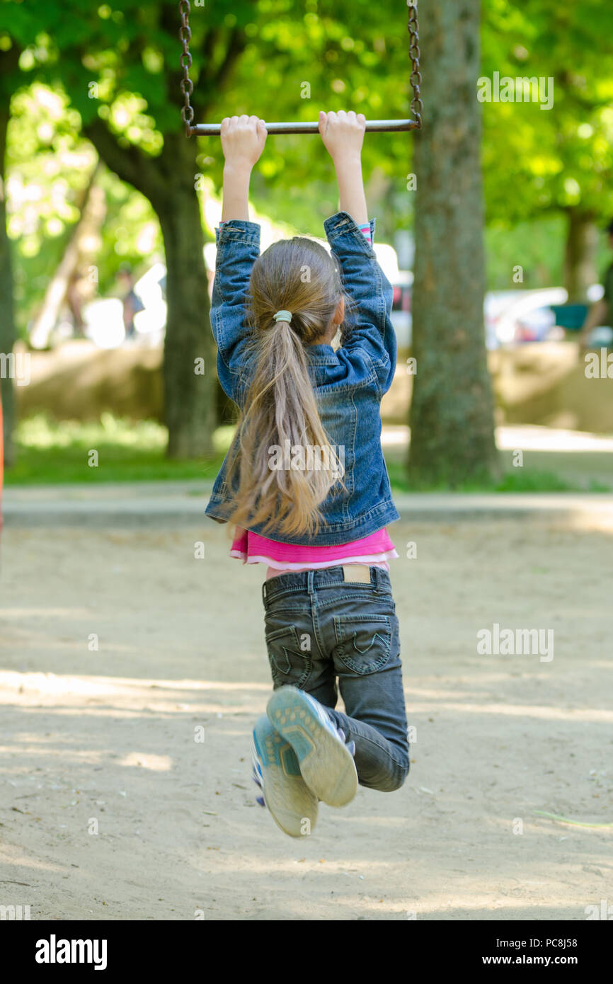 A girl is riding a metal ladder on chains in a playground Stock Photo ...