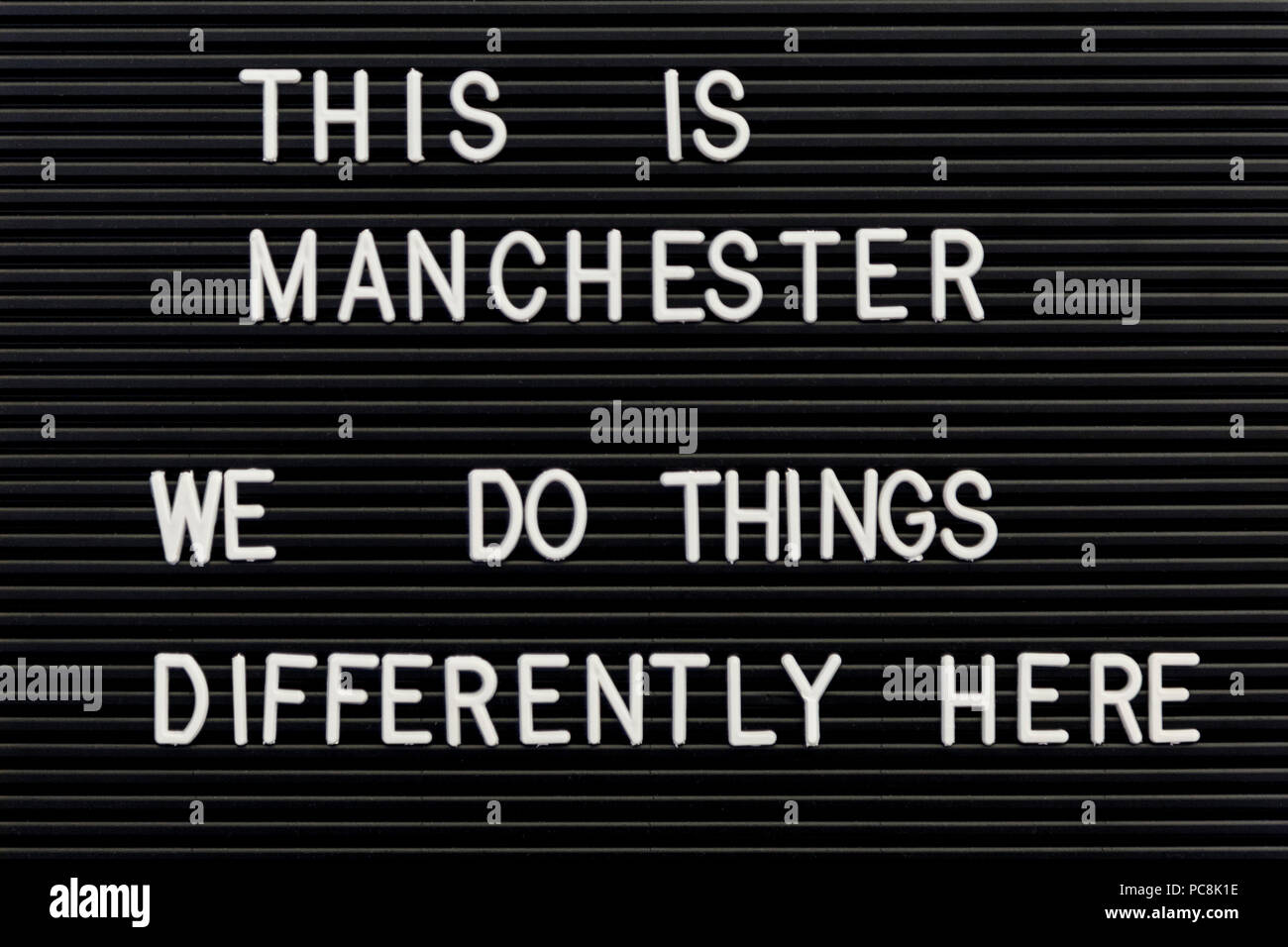 'This is Manchester, We do things differently here' motto on a wall written in plastic toy letters, Manchester, UK Stock Photo