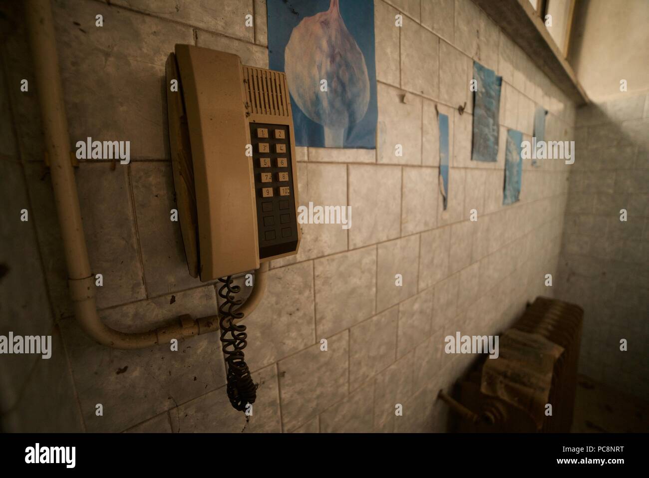 Old style telephone mounted to the wall inside an abandoned building Stock Photo