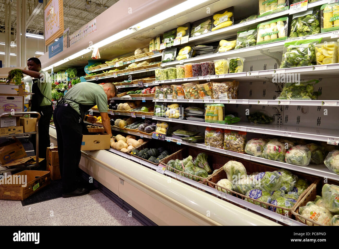 Grocery clerk working in produce aisle of supermarket store Stock Photo by  ©FreeProd 118794062