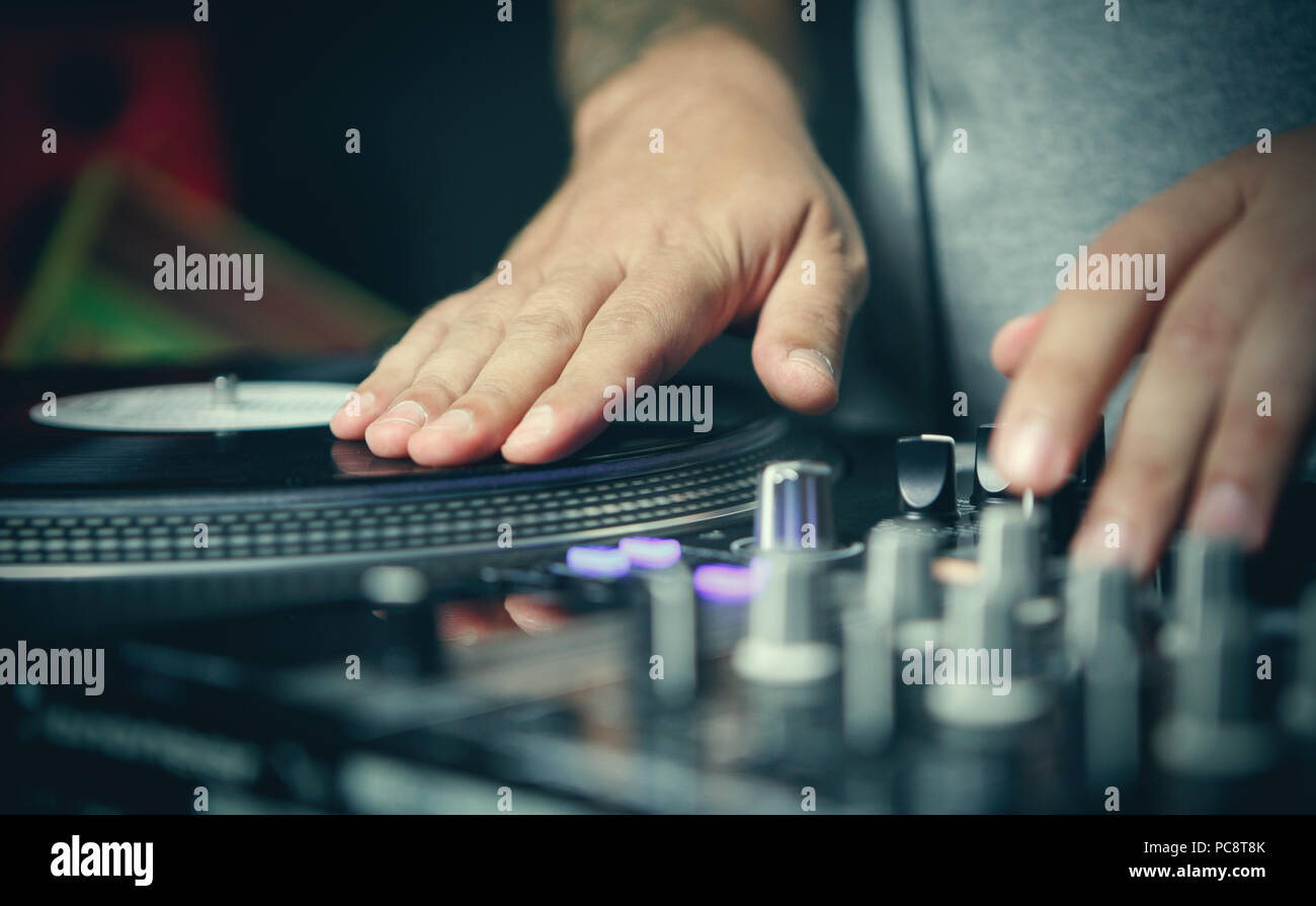 Club party dj scratches vinyl records on turntable player device