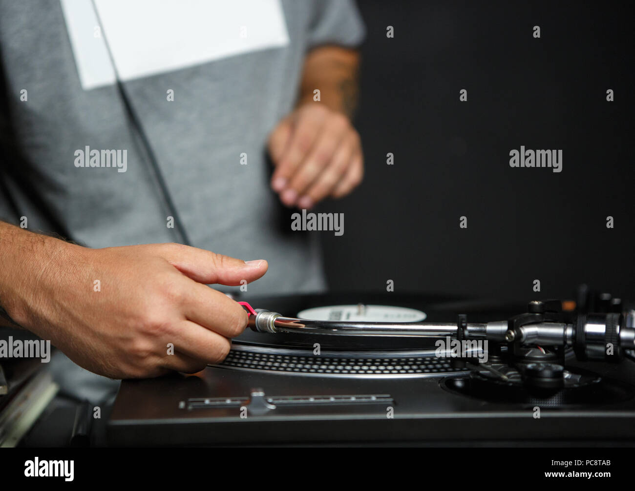 Party dj puts turntables needle on a record with music to play set in