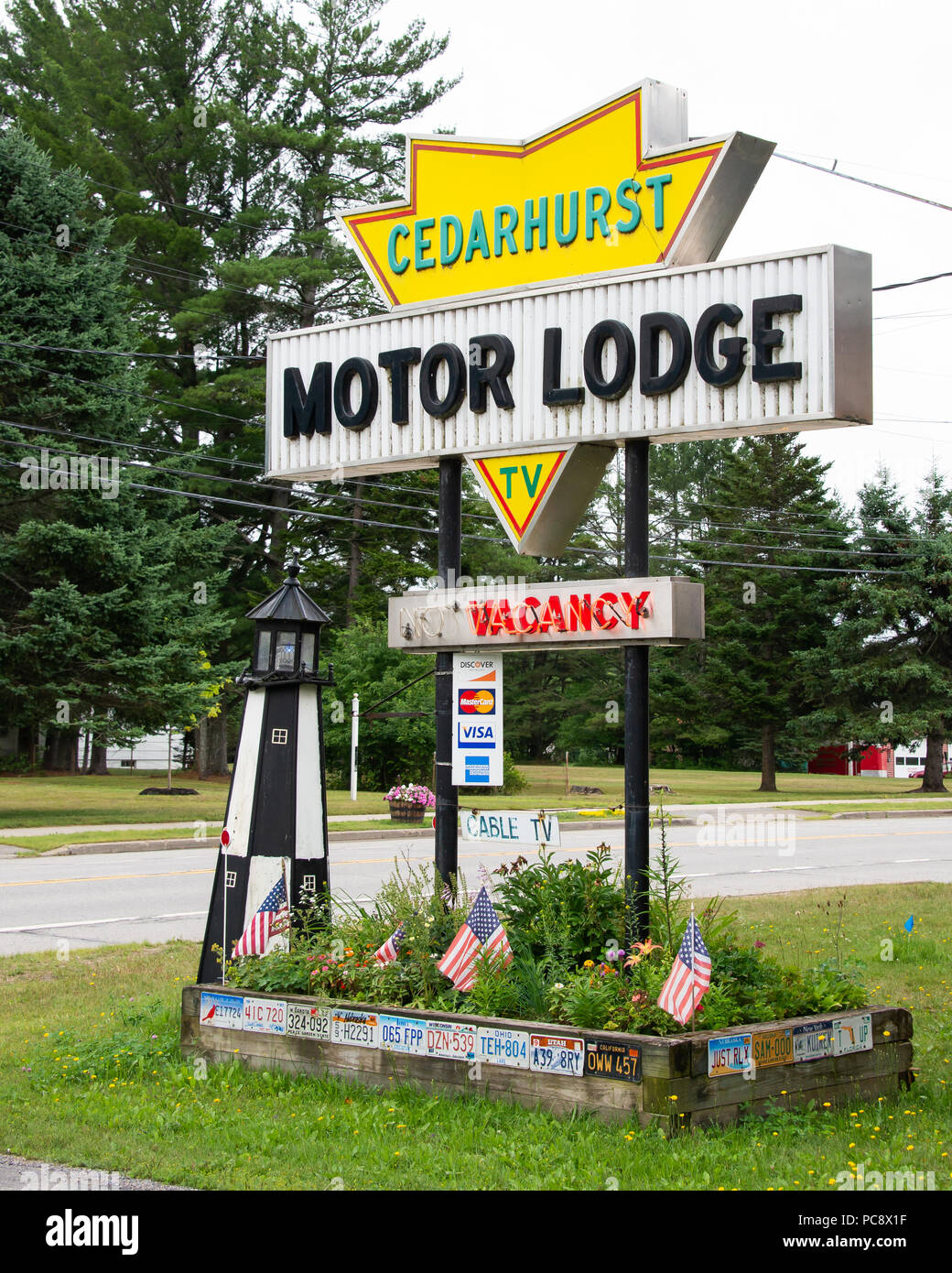 A Cedarhurst Motor Lodge sign with flower garden, lighthouse and American flags in Speculator, NY USA Stock Photo
