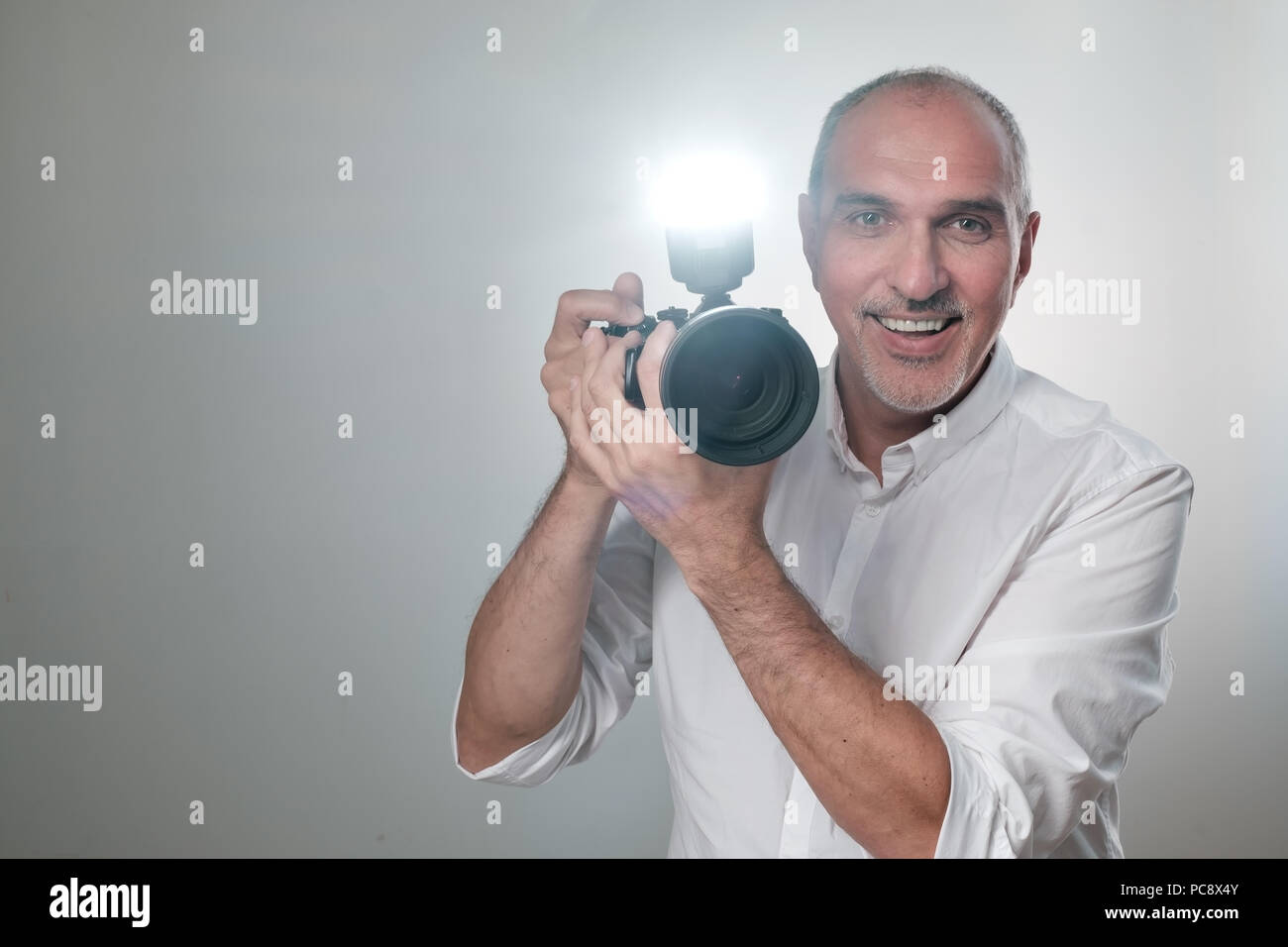 Studio shot of young multi-ethnic Asian man with camera against brown background Stock Photo