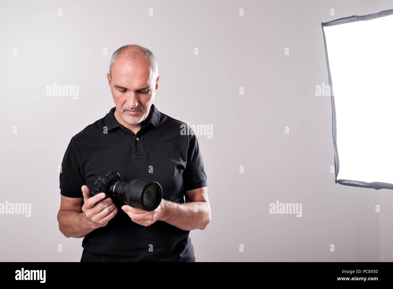 Studio shot of young multi-ethnic Asian man with camera against brown background Stock Photo