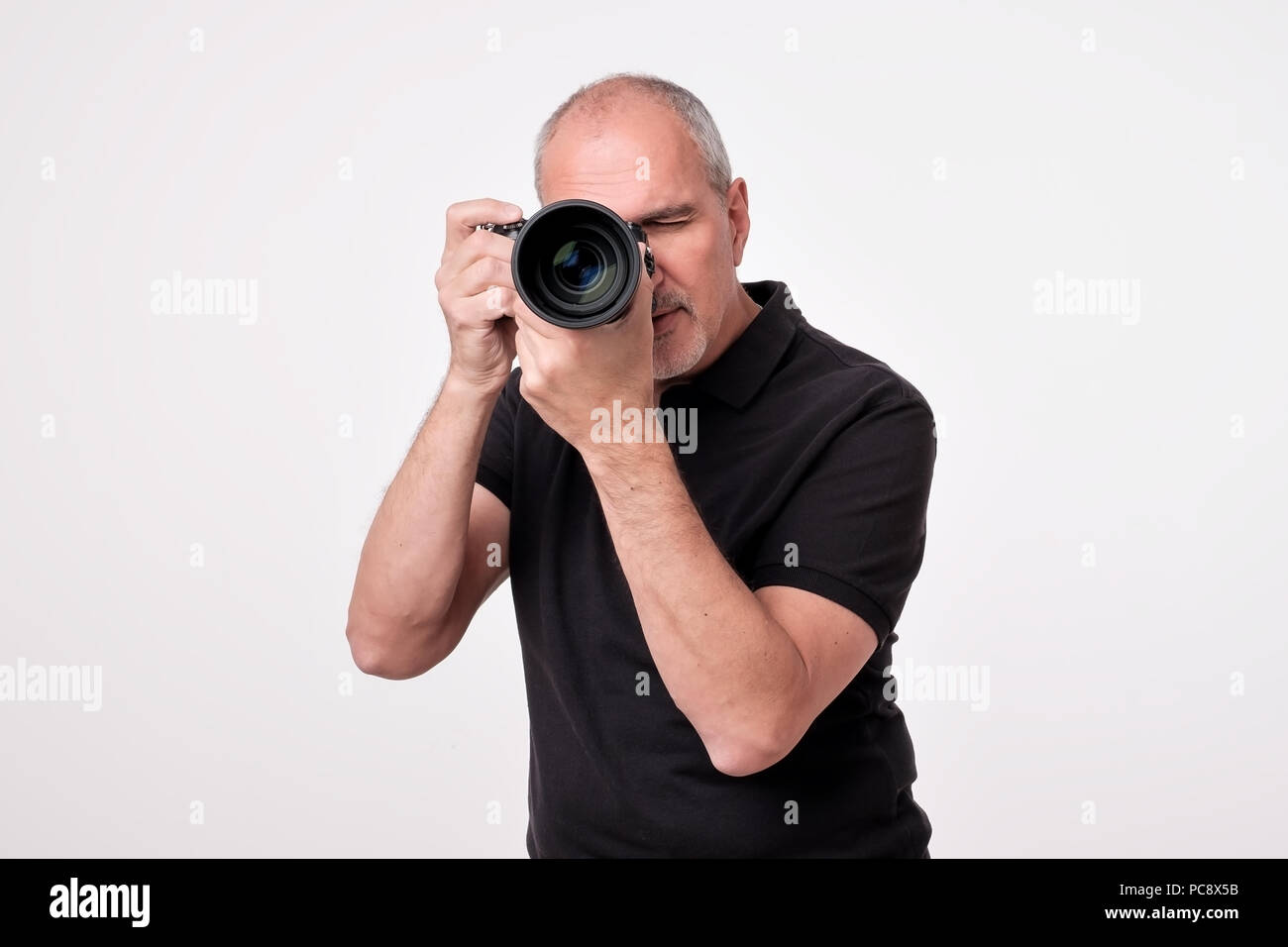 Studio shot of young multi-ethnic Asian man with camera against brown background Stock Photo