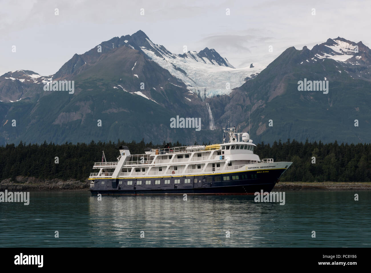 Lindblad National Geographic Sea Bird at anchor in front of a mountain with a hanging glacier in SE Alaska, USA. Stock Photo