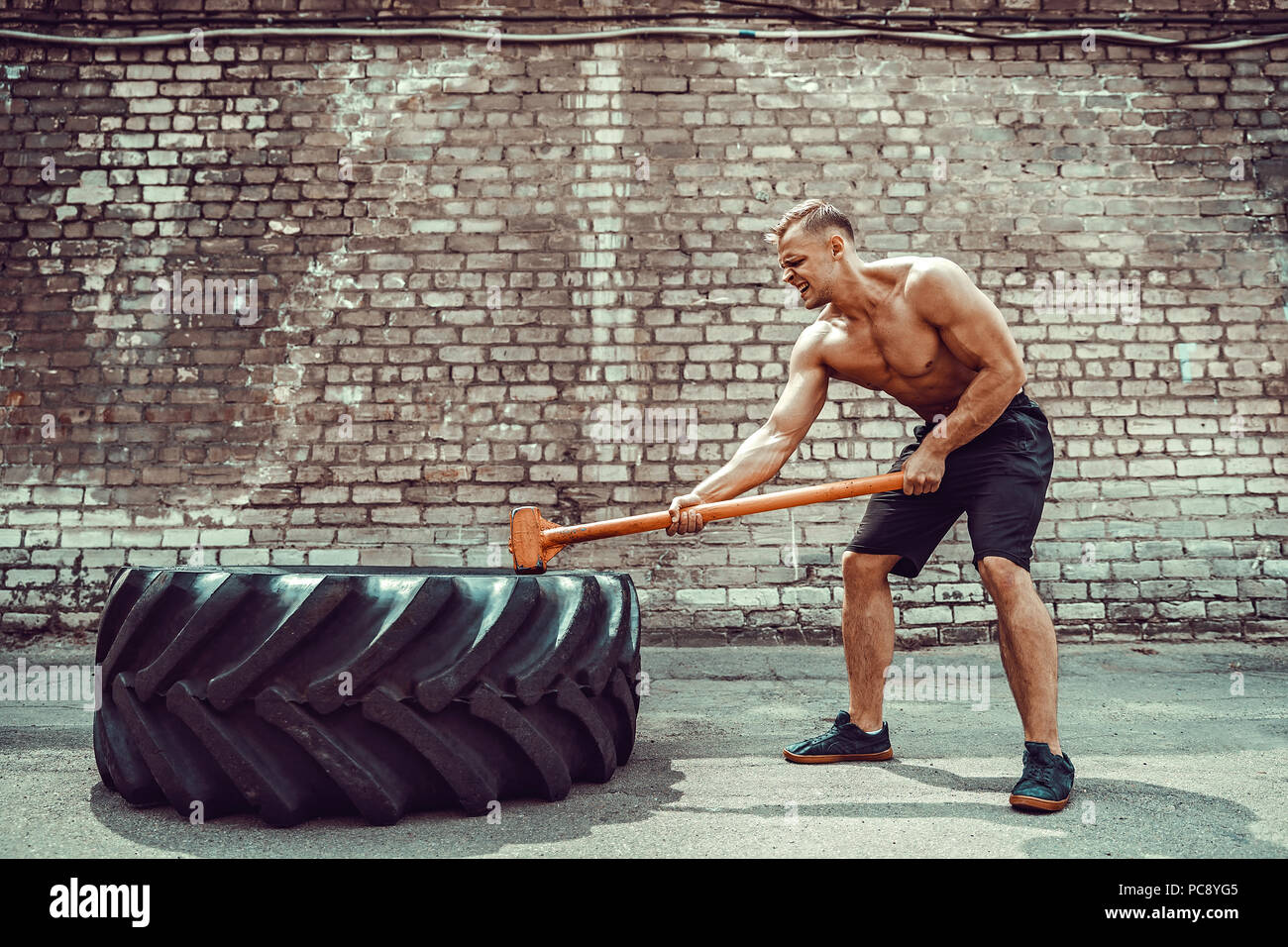 Sport Fitness Man Hitting Wheel Tire With Hammer Sledge Crossfit