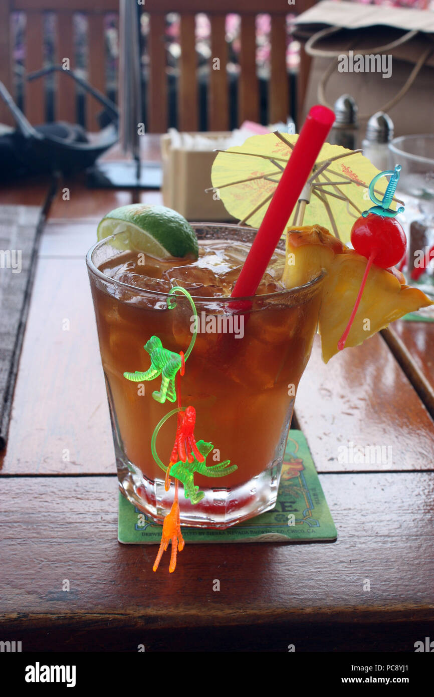 A mai tai drink garnished with pineapple, cherry, lime, an umbrella and
