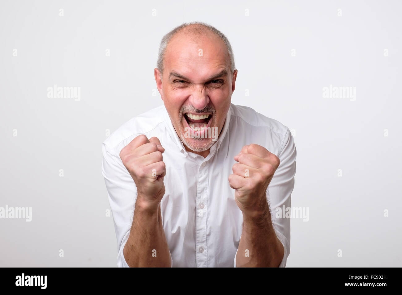Mature hispanic man is happy with his win. He is holding his fists and shout Wow. Stock Photo