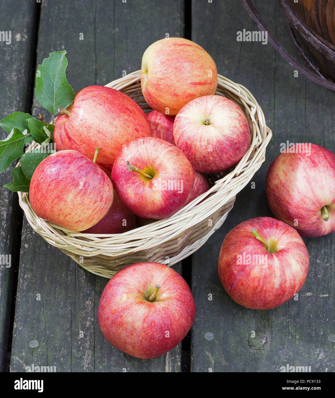 Bunch of fresh red apples and basket on a rustic wooden surface Stock ...