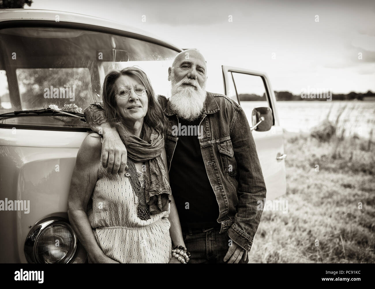 An old hipster couple posing in front of their camper van  Stock Photo