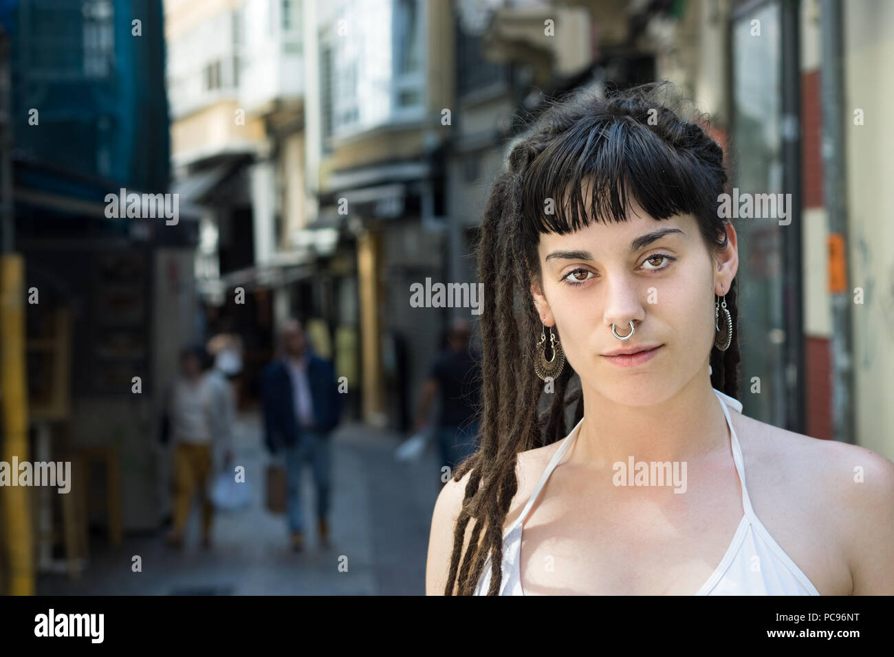 La Coruña, Spain - July 13th, 2018: Portrait of a local young woman in the street with rastafarian look, dreadlocks and a piercing in the nose. Stock Photo