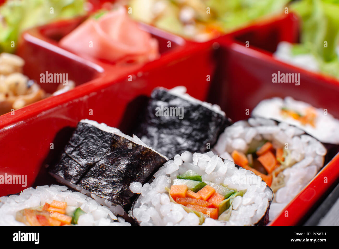 Fresh food portion in japanese bento box with salad, main course. Sushi roll with vegetables