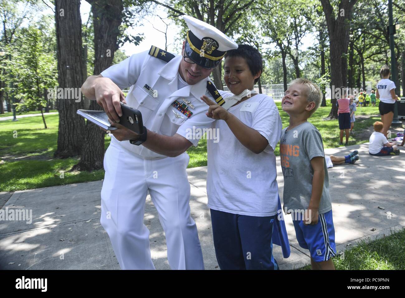 180724-N-VH385-0167 FARGO, N.D. (July 24, 2018) - Lt. Mack Jamieson, a native of Fulton, Miss. assigned to the Navy Office of Community Outreach, takes a selfie with children of the YMCA and local Boys and Girls Clubs at Island Park in Fargo, N.D. during Fargo-Moorhead Metro Navy Week, July 24, 2018. The Navy Office of Community Outreach uses the Navy Week program to bring Navy Sailors, equipment and displays to approximately 14 American cities each year for a week-long schedule of outreach engagements designed for Americans to experience first hand how the U.S. Navy is the Navy the nation nee Stock Photo
