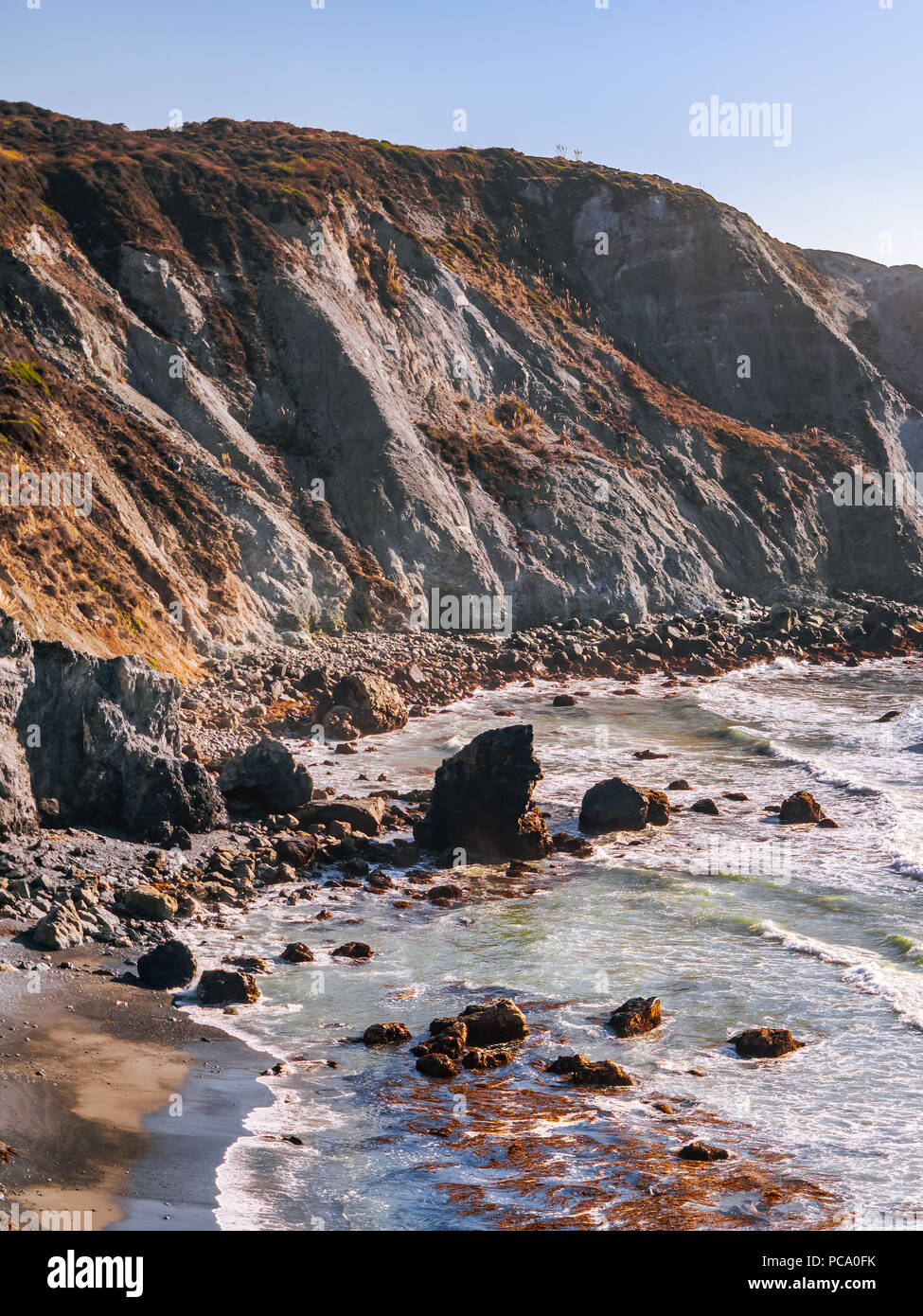 Scenic coastline along the Pacific Coast near Big Sur, California. Ocean waves crashing down on steep cliffs of Willow Creek Beach in early evening. Stock Photo