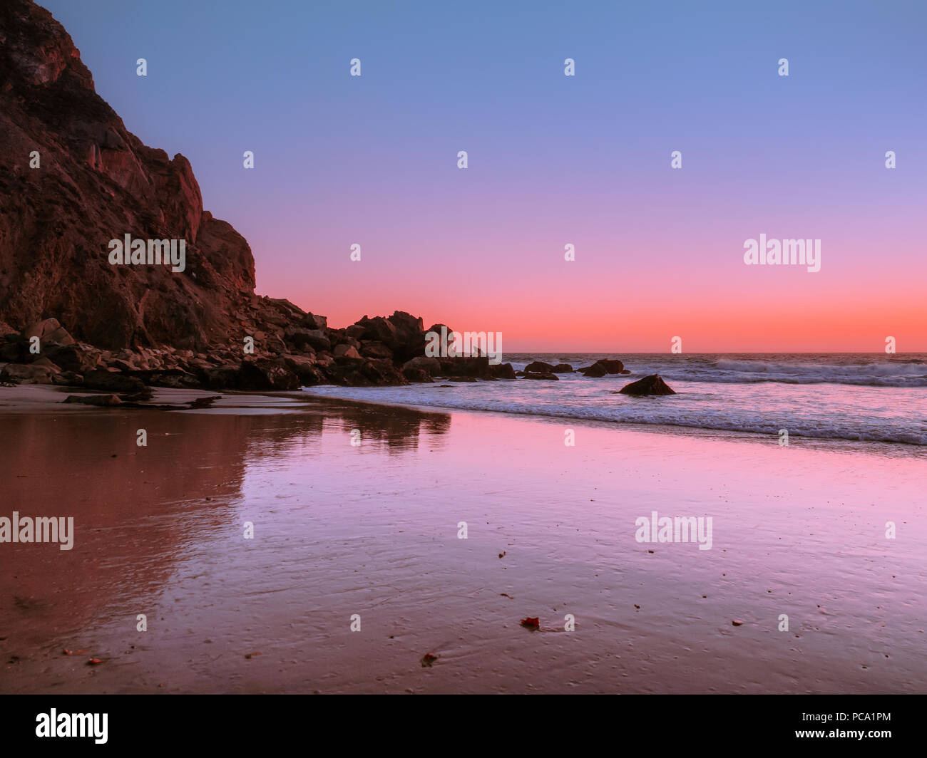 Famous Pfeiffer Big Sur Beach at sunset. Rocky cliff on the California coast. Low tide exposes the wet sand with sharp texture in the foreground. Stock Photo