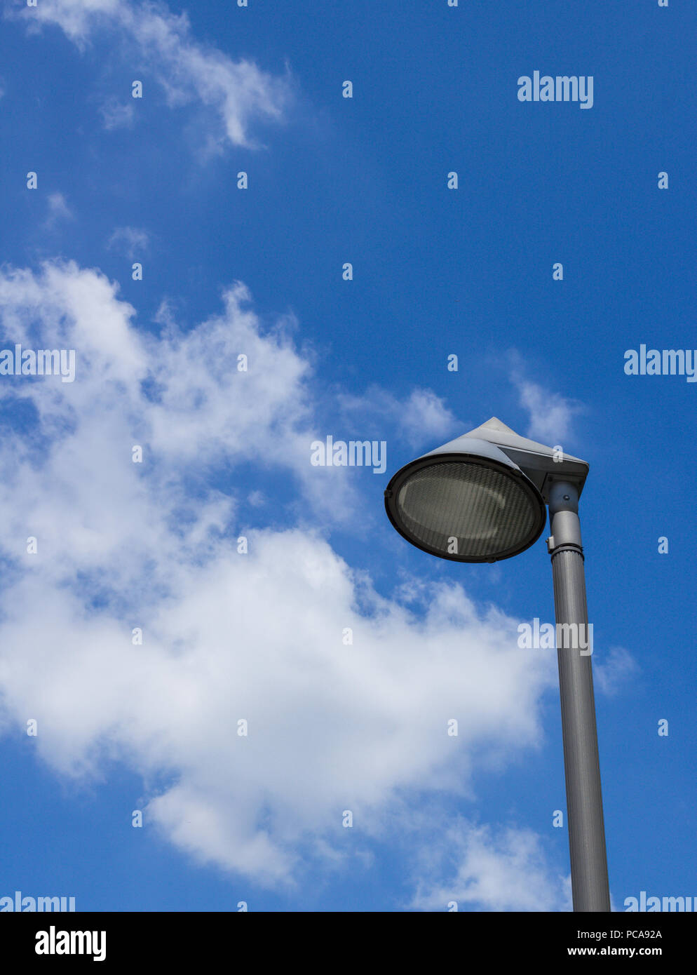 Close - up of modern street lamp of round shape on a blue sky with some white clouds. Space for text. Stock Photo