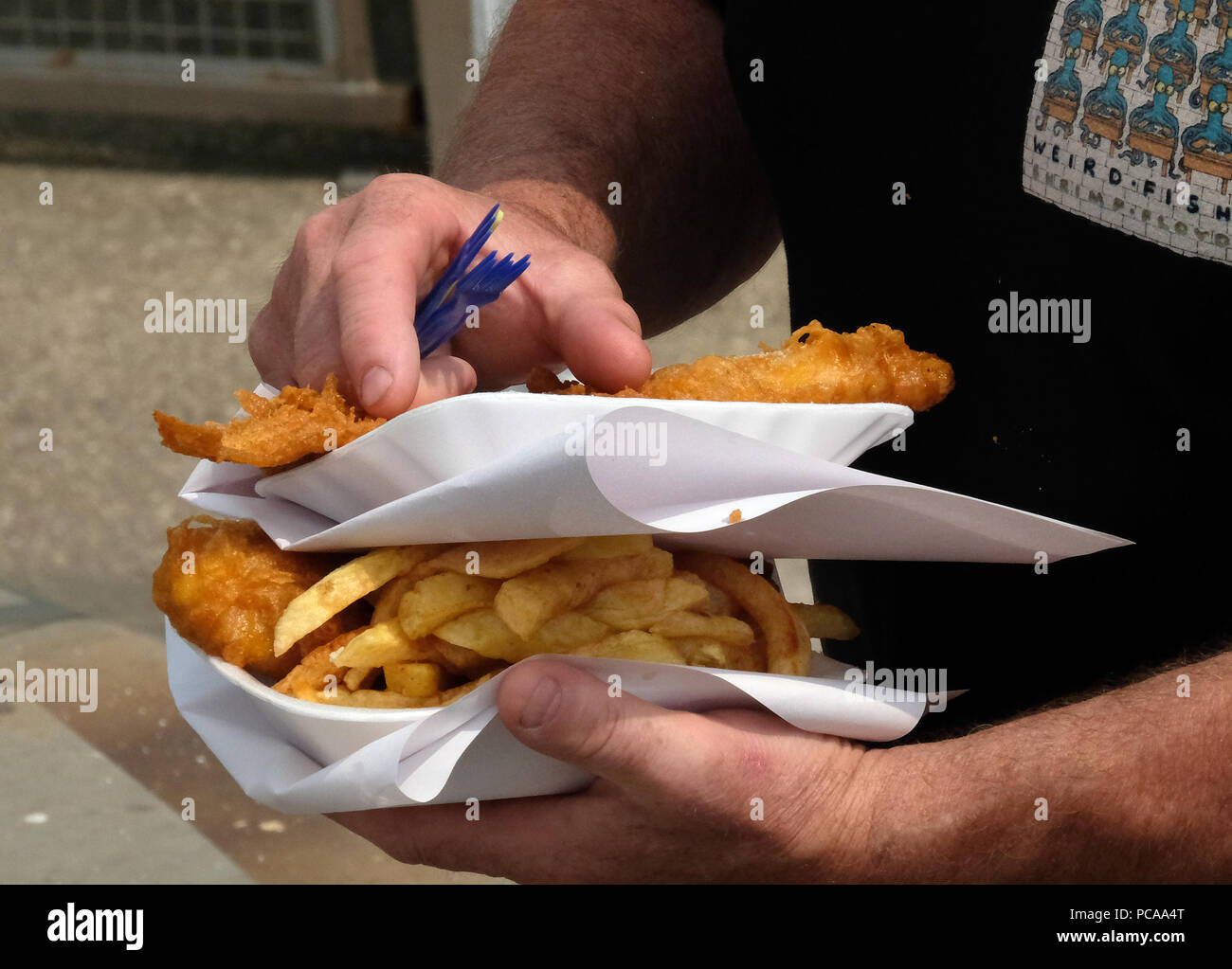 Man carrying two trays of fish and chips. Stock Photo