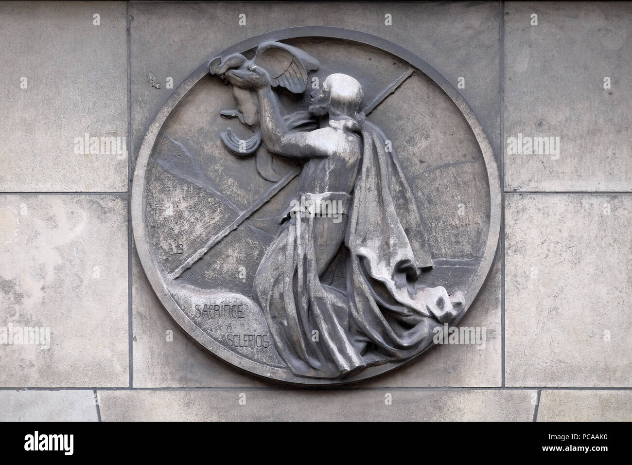 Sacrifice to Asclepius, god of medicine in ancient Greek religion and mythology. Stone relief at the building of the Faculte de Medicine Paris, France Stock Photo