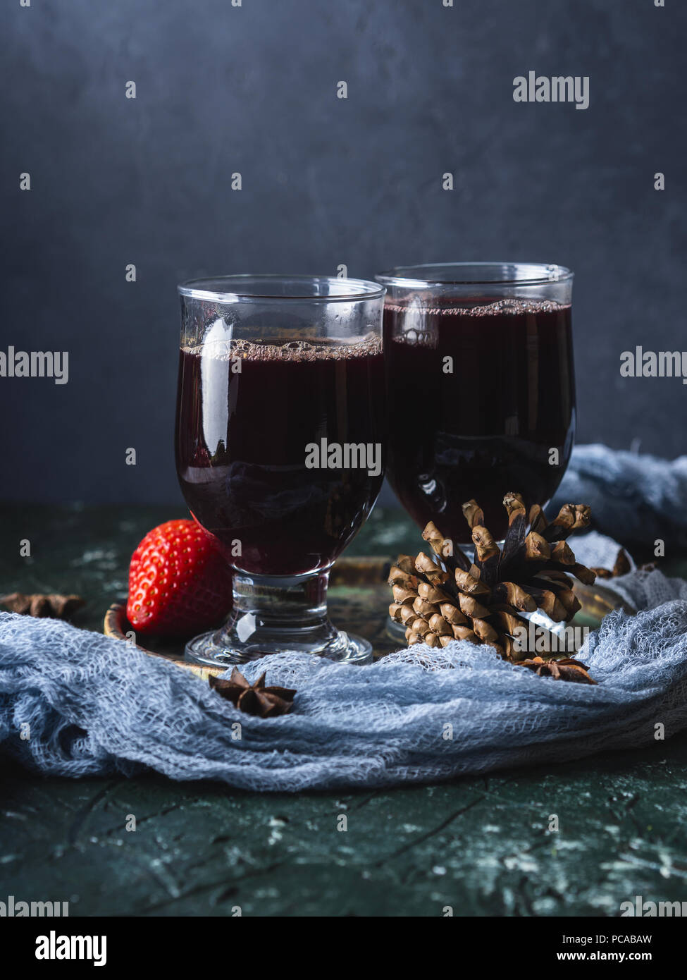 Hot mulled wine in stemmed glasses over dark background Stock Photo