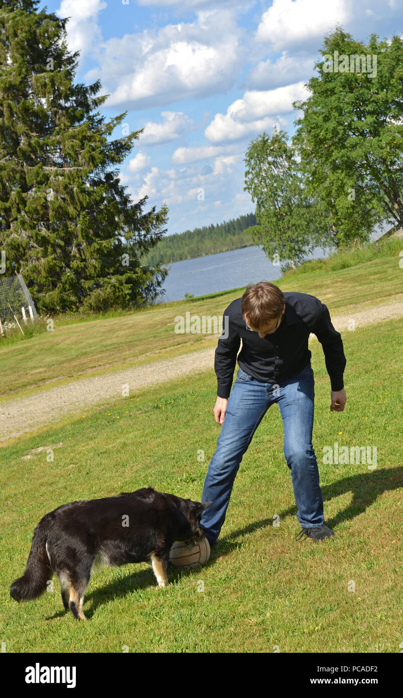 Young man plays with dog in football in Finnish Lapland. Dangerous moment Stock Photo