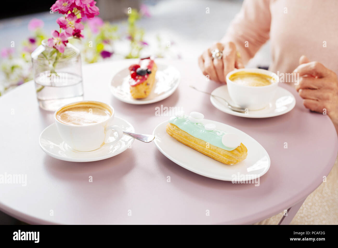 Dainty eclair and coffee remaining on surface Stock Photo