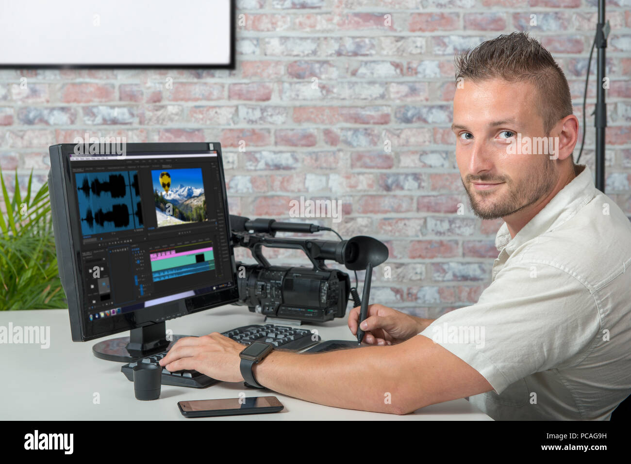 a video editor with computer and professionnal video camera Stock Photo Alamy