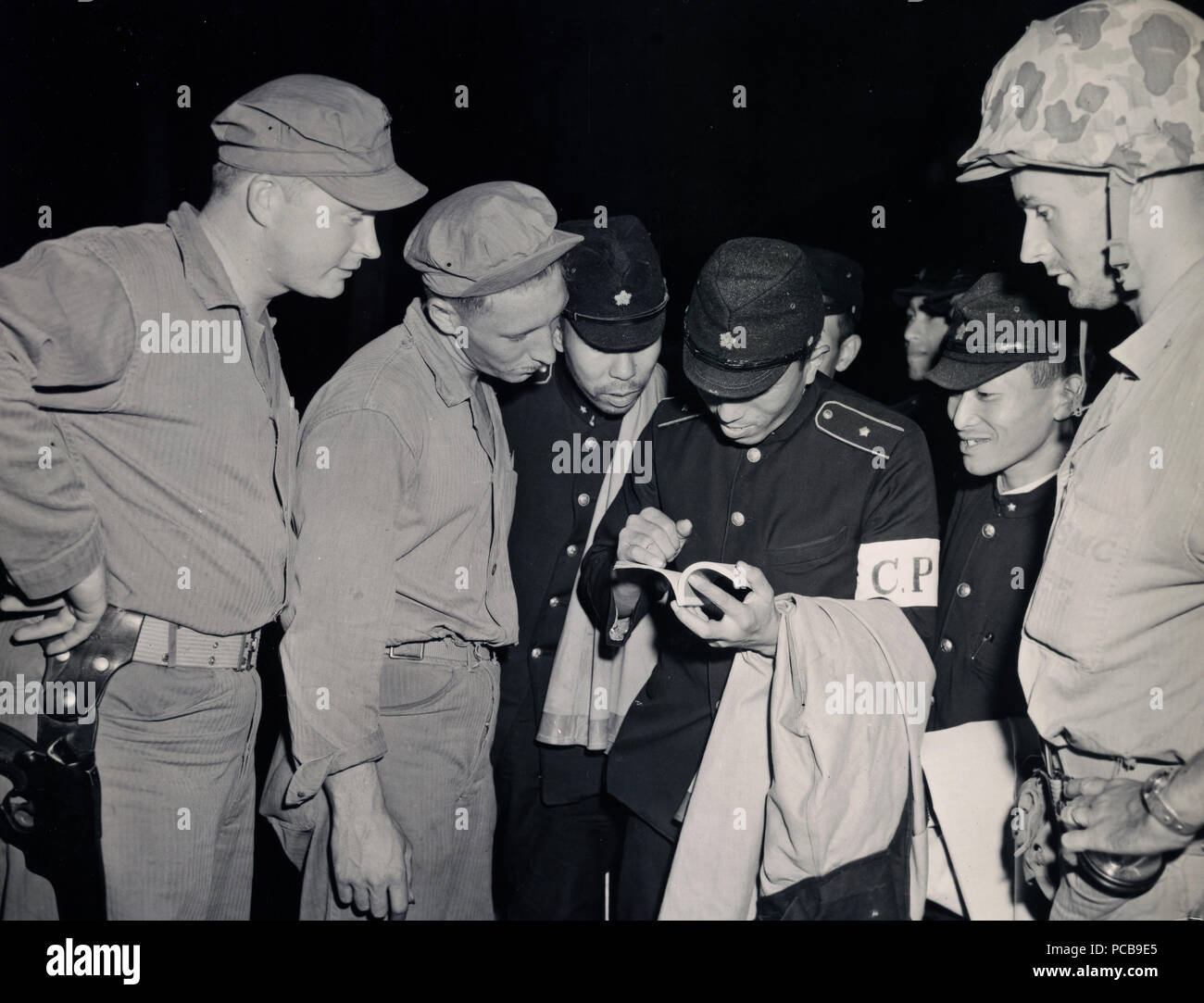 Fifth Marine division occupation forces on Japan turn to a phrase book to ask Japanese civliliian police force question s in Sasebo Japan Stock Photo