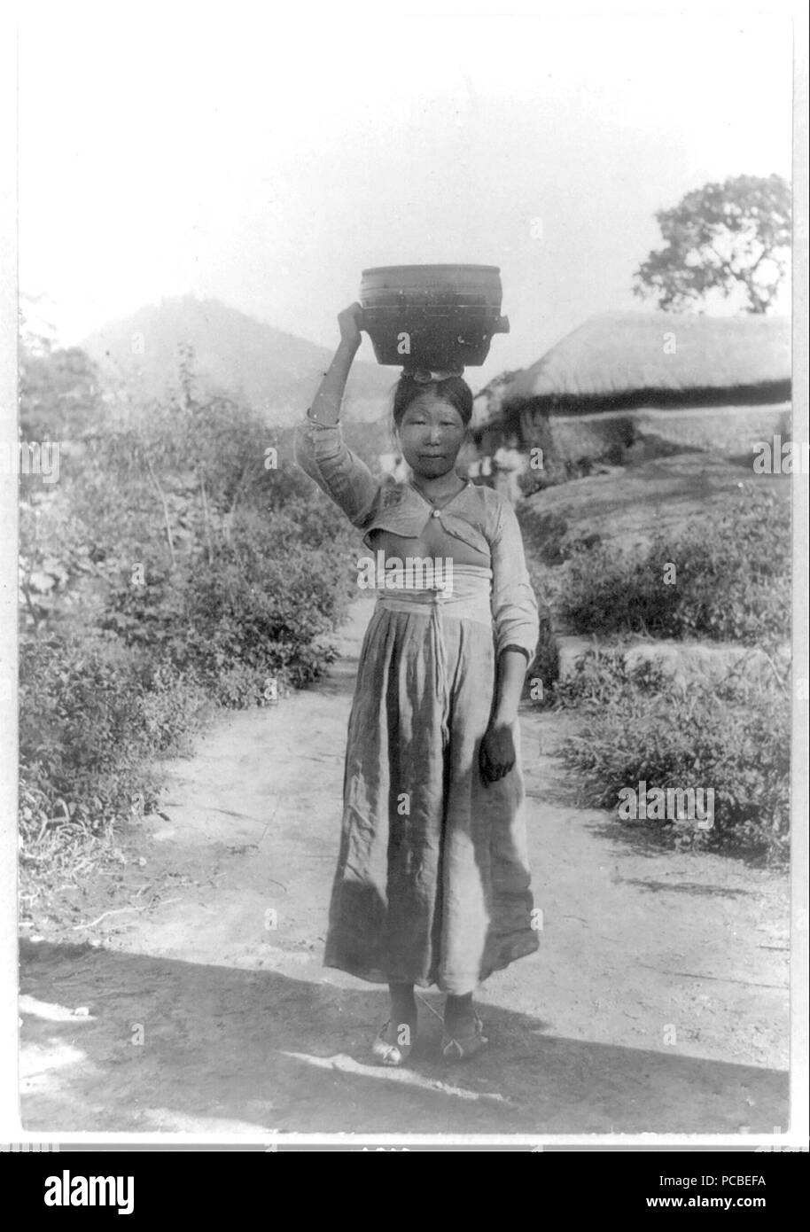 Woman carrying load [tub] on her head. 1910-1920 Korea Stock Photo