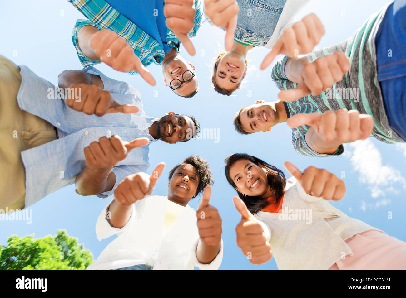 happy friends showing thumbs up standing in circle Stock Photo
