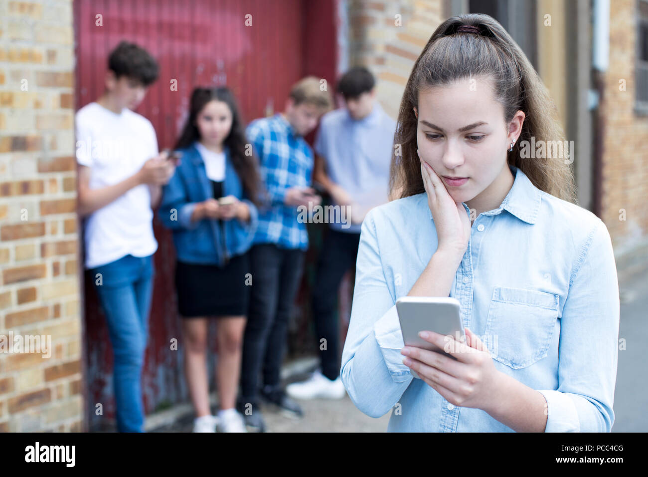 Worried Teenage Girl Being Bullied By Text Message Stock Photo